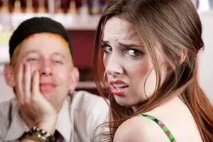 Woman looking over her shoulder with a unhappy look on her face as her blind date smiles at her across the table.