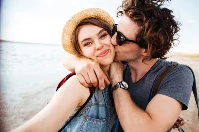 Couple who met through an Australian matchmaker embracing on the beach taking a selfie