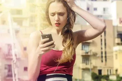 Young woman looking confused by a text message