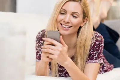 Woman smiling at a funny Tinder message on her phone